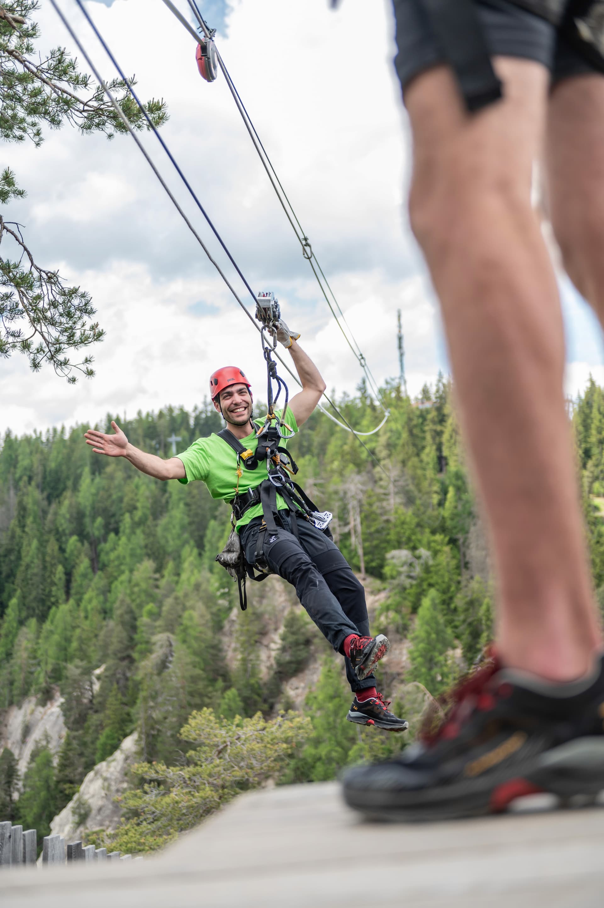 Instructor arriving on zipline waving from the cable
